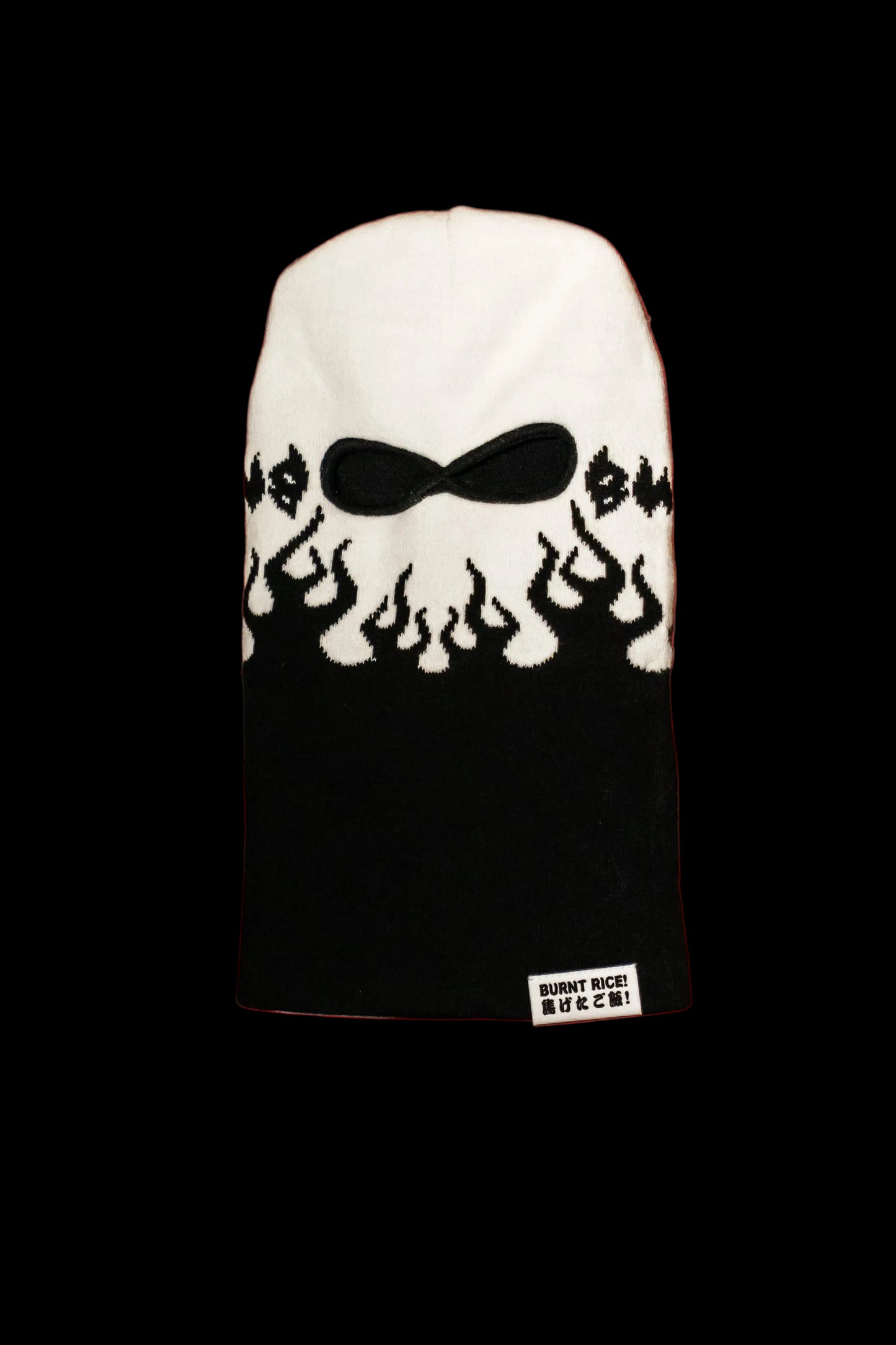 A black and white knit balaclava face covering with a stylized black eye and flame graphic across the forehead, shown against a solid red background. A small white brand label reading 'BURNT BEE' is visible at the bottom.